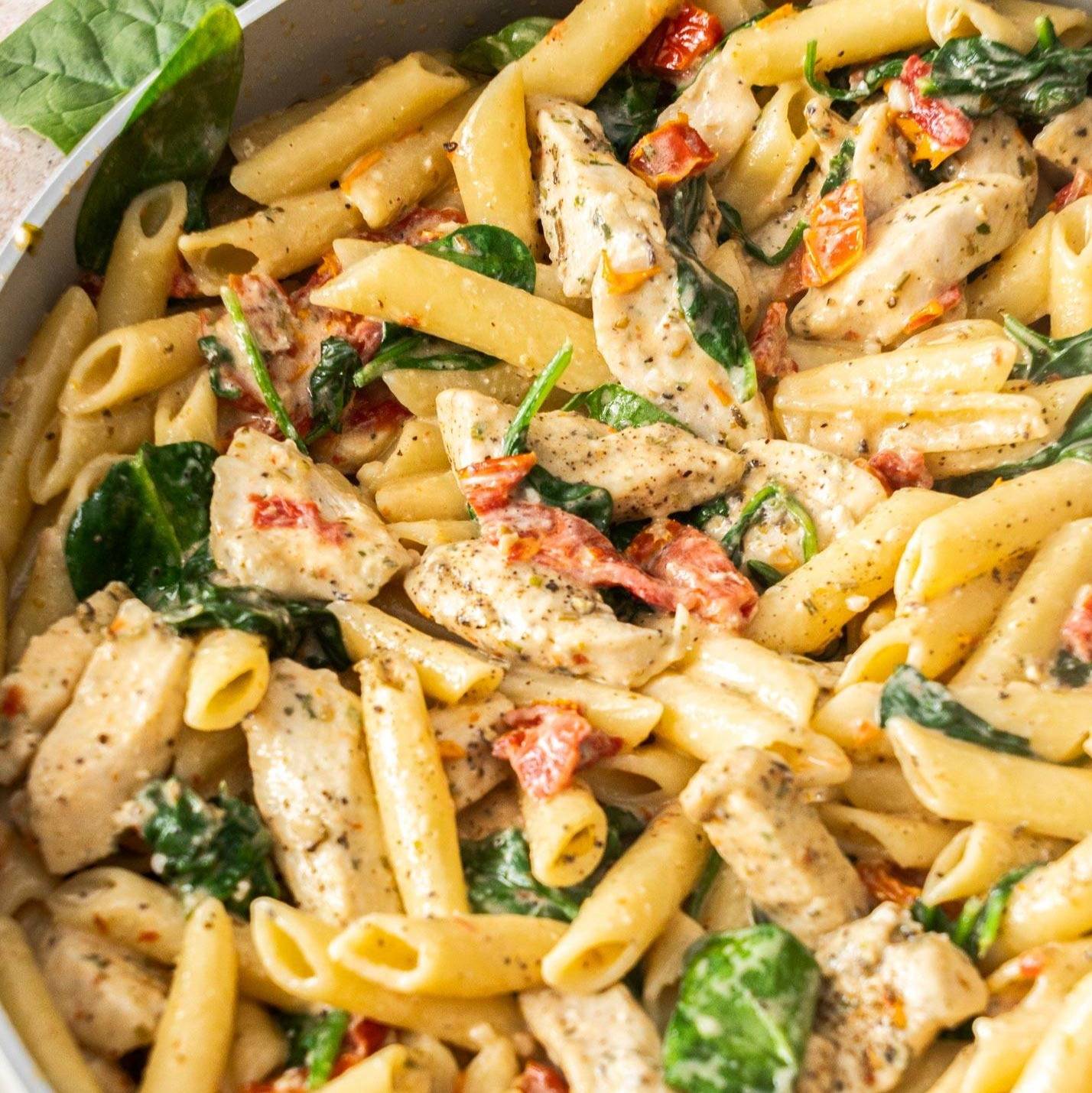 Top down view of a pan filled with creamy penne pasta and chicken.