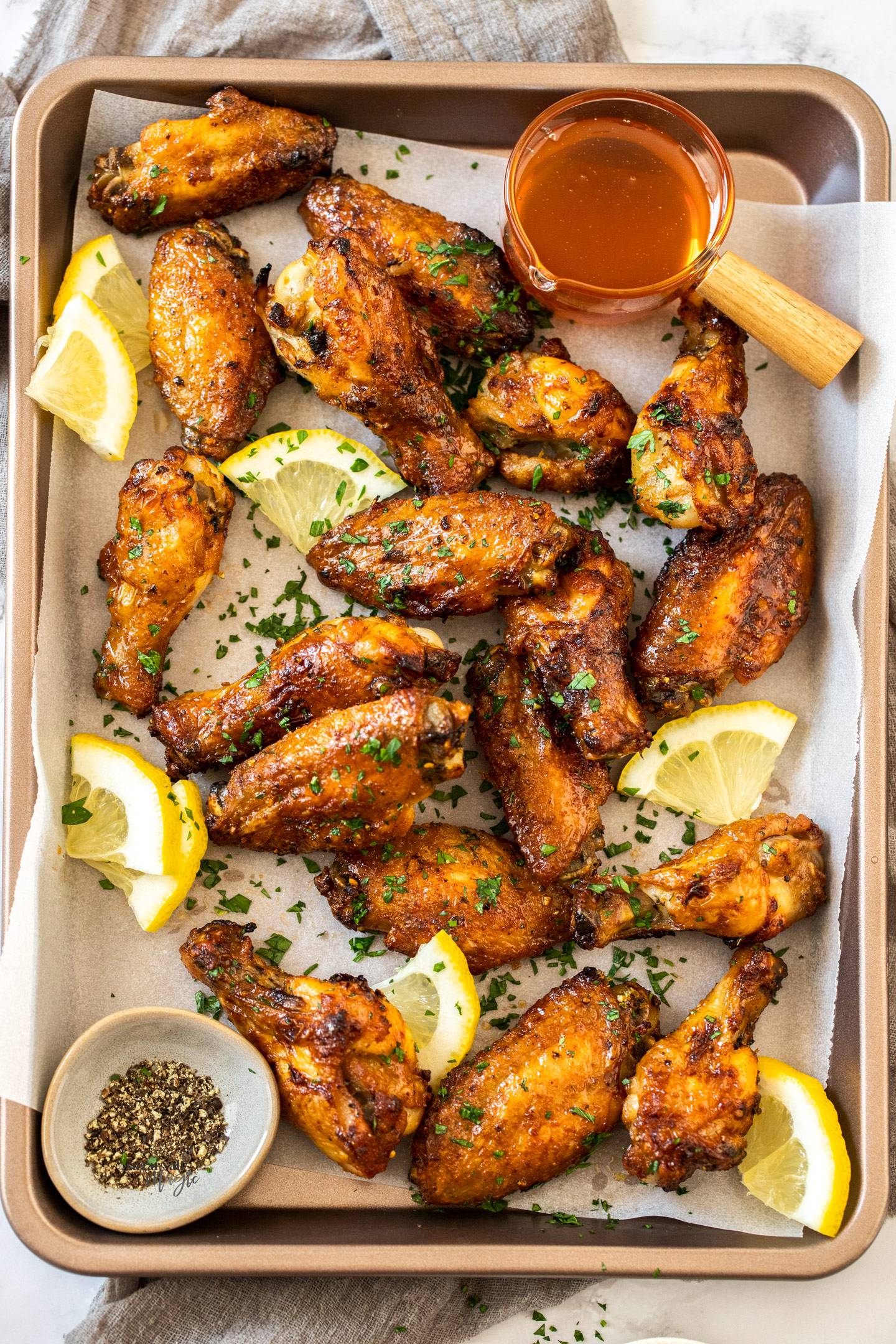 Top down view of a batch of lemon pepper wings on a baking tray.