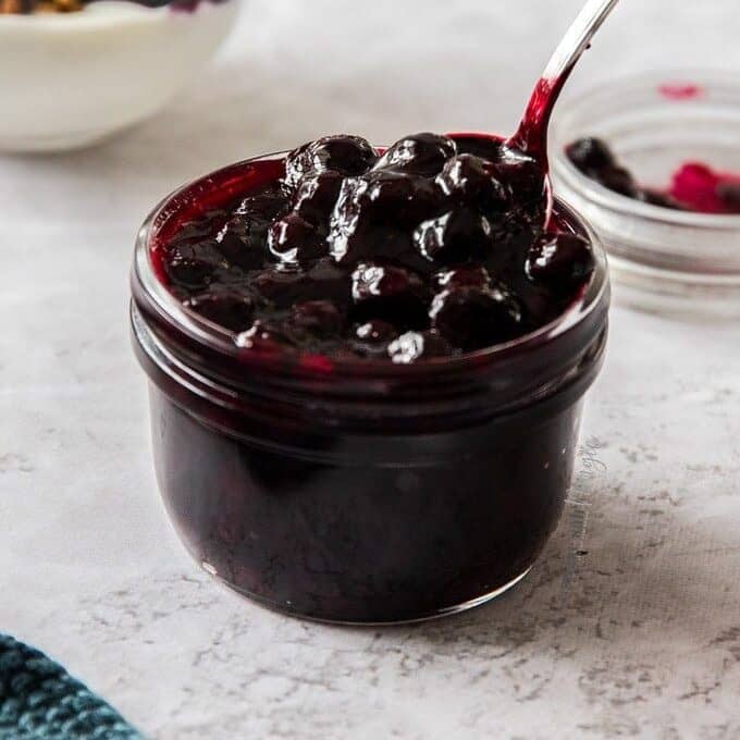 A small glass jar filled with blueberry topping.