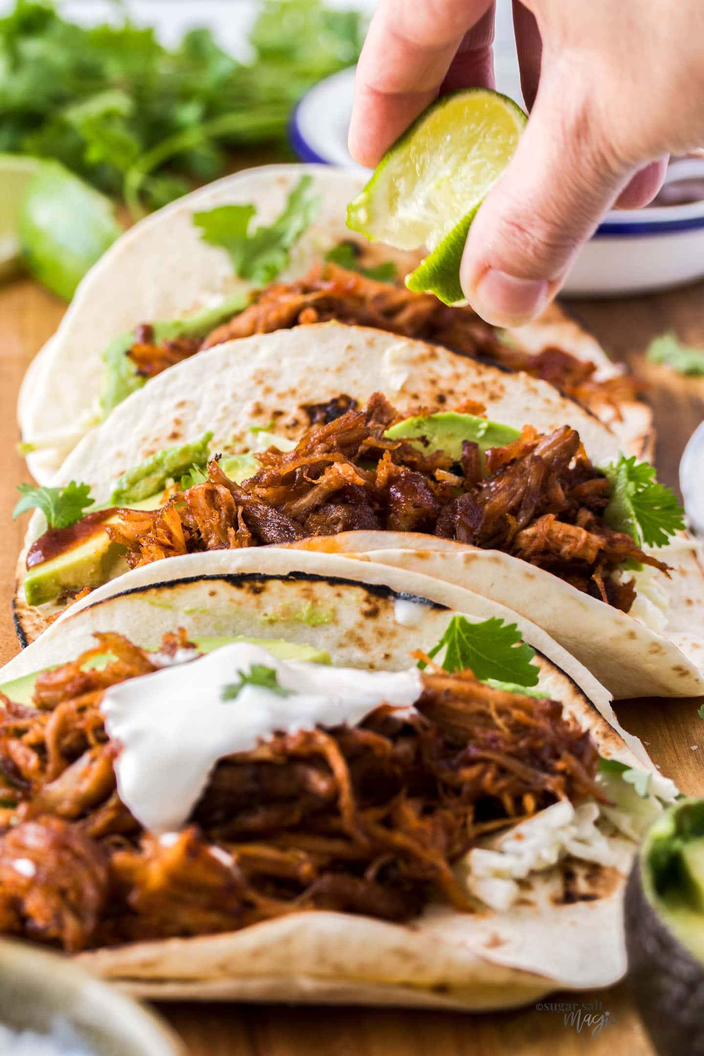 Closeup of three tacos filled with pulled pork.