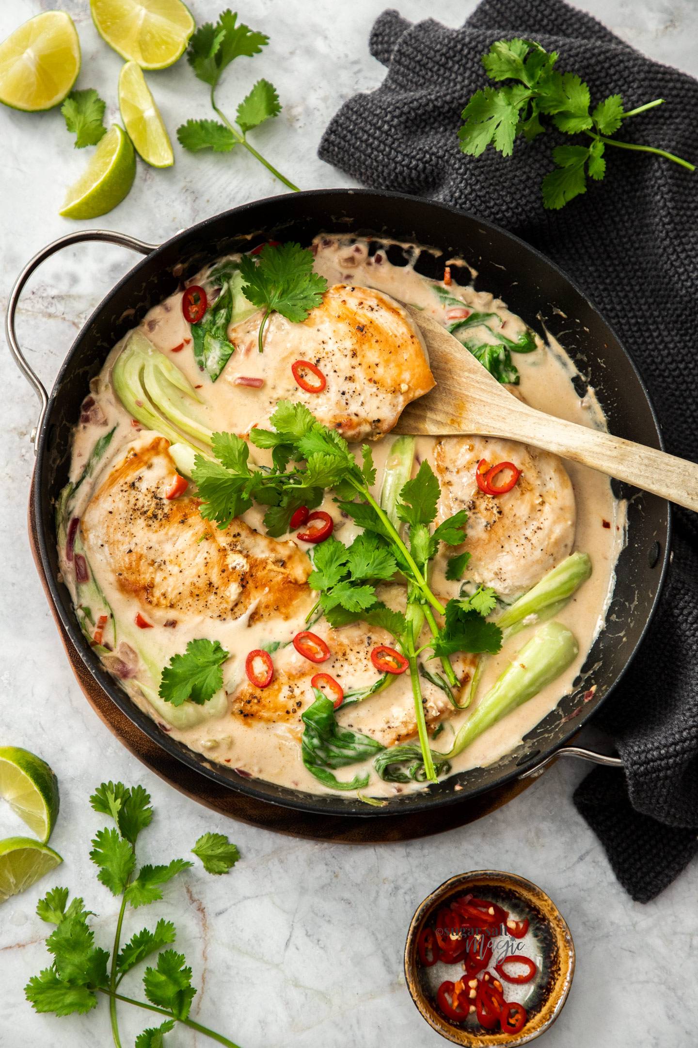 Top down view of cooked chicken in a creamy sauce in a pan.