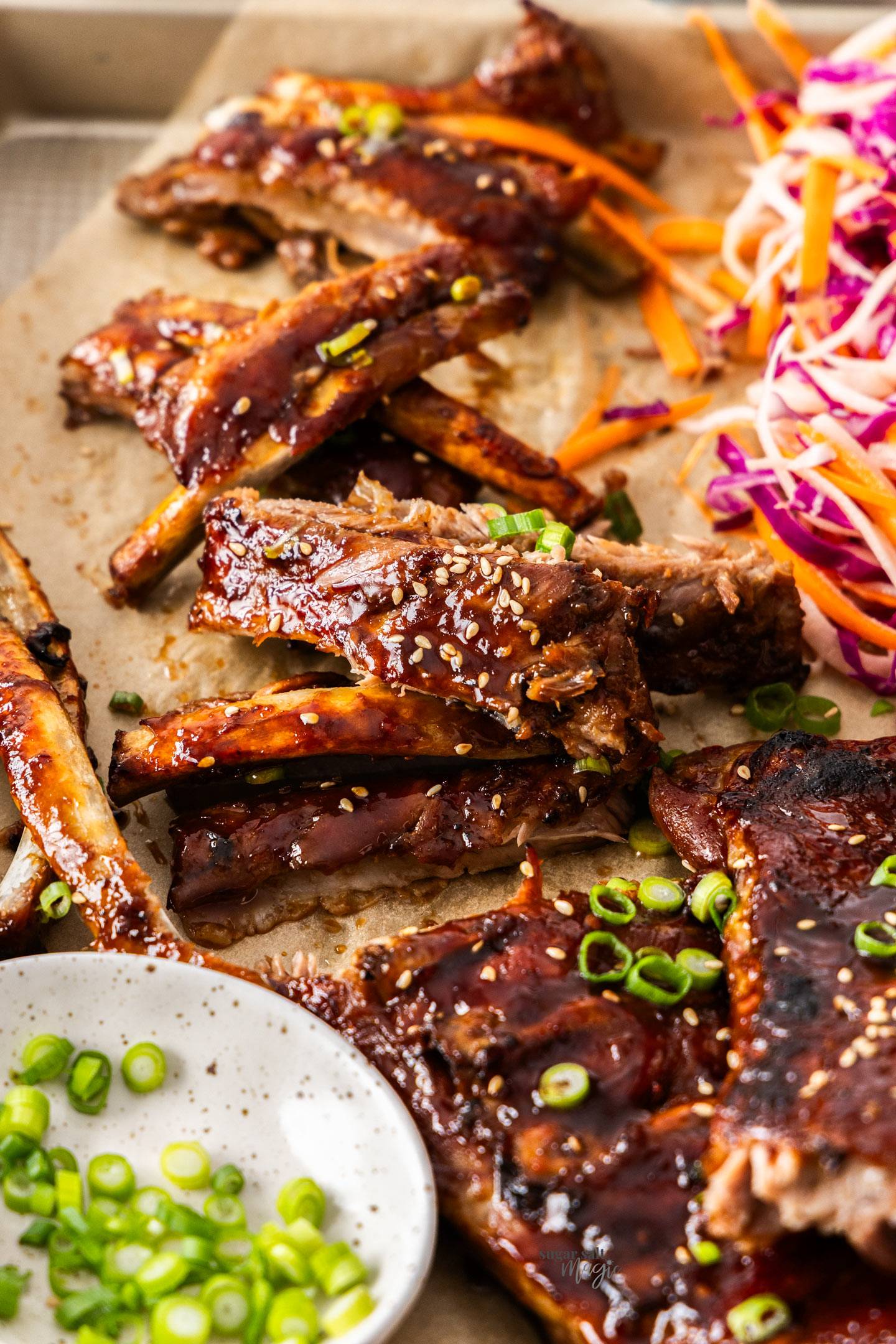 A batch of cut up sticky Asian pork ribs on a baking tray.