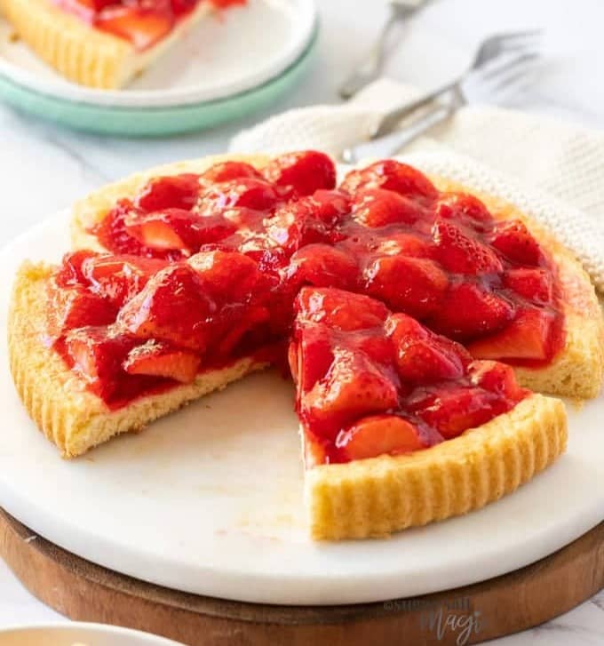 A strawberry sponge flan on a marble platter.