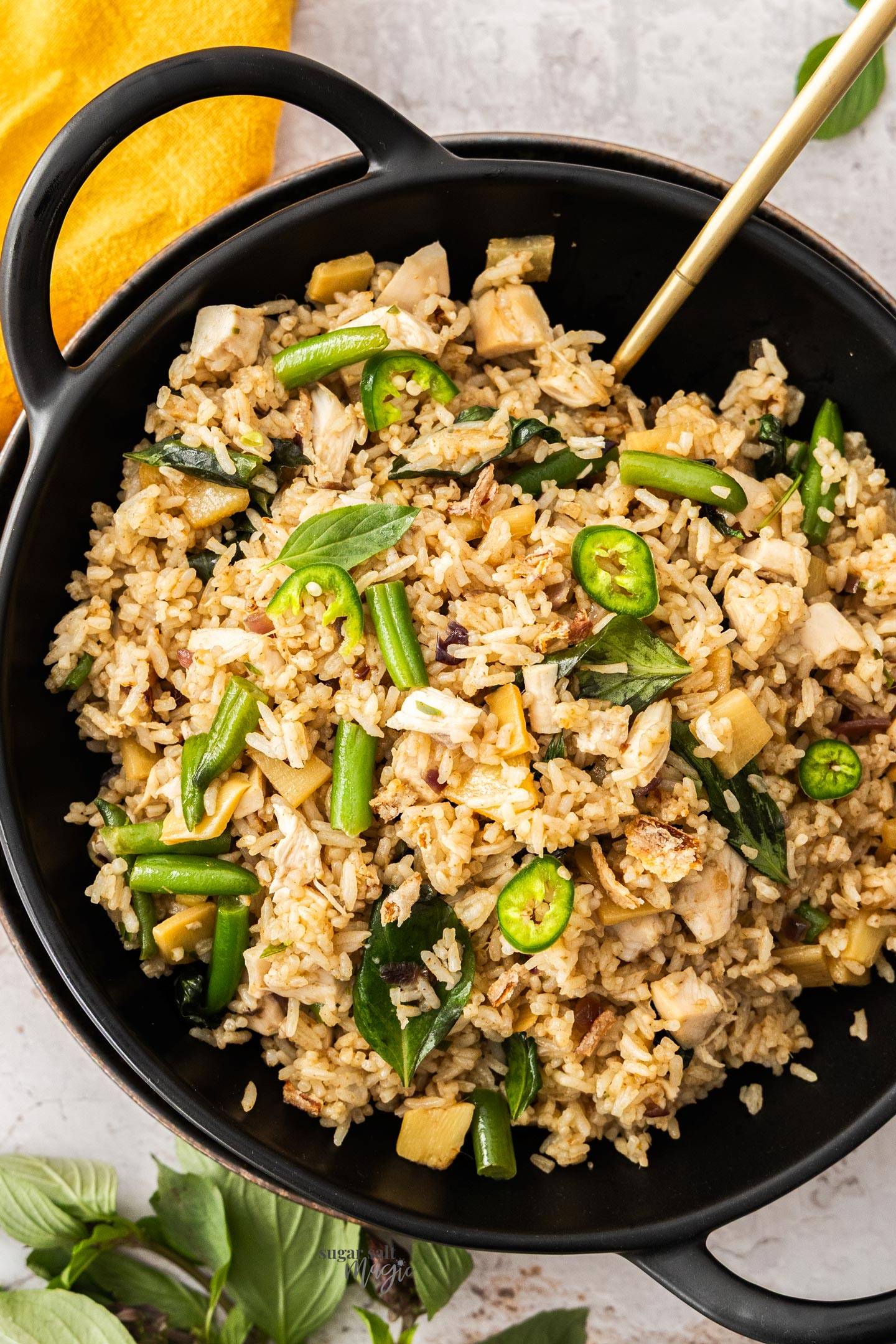 Top down view of Thai fried rice in a black bowl with handles.