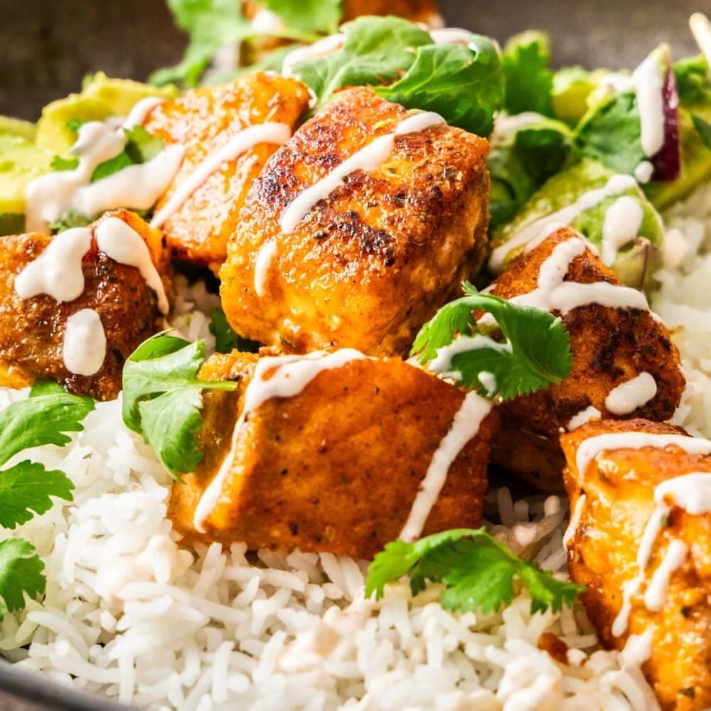 Close up of cubes of cooked salmon on a bed of rice.