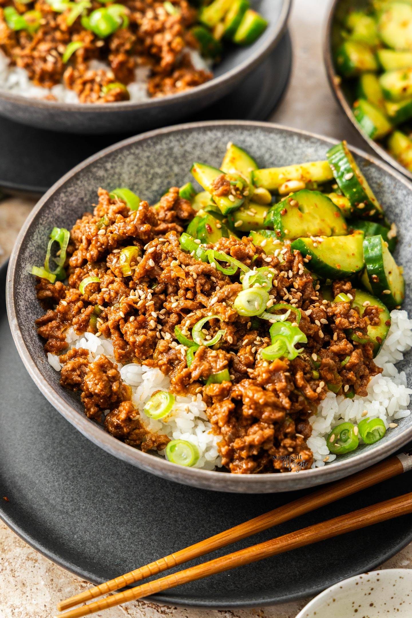 A bowl of gochujang over rice with cucumber salad on the side.