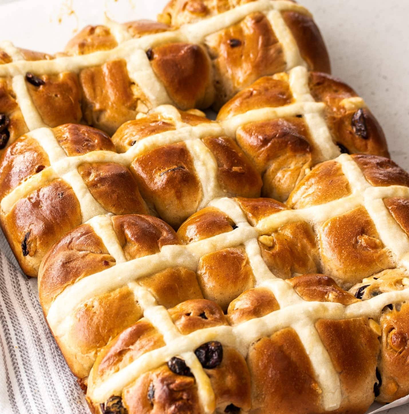 A batch of 12 hot cross buns on a stone surface.