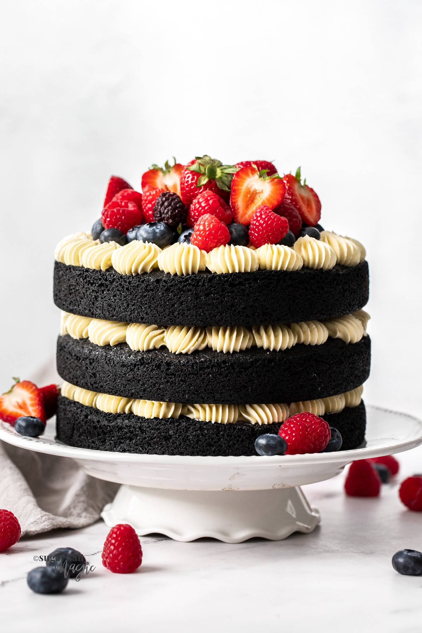 A tri-layered chocolate cake with Swiss meringue buttercream and topped with berries.