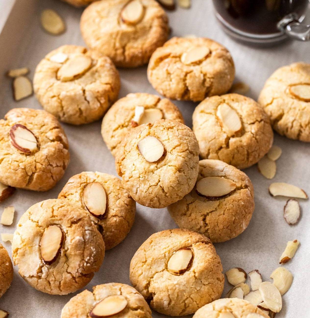 A pile of round cookies topped with almonds.