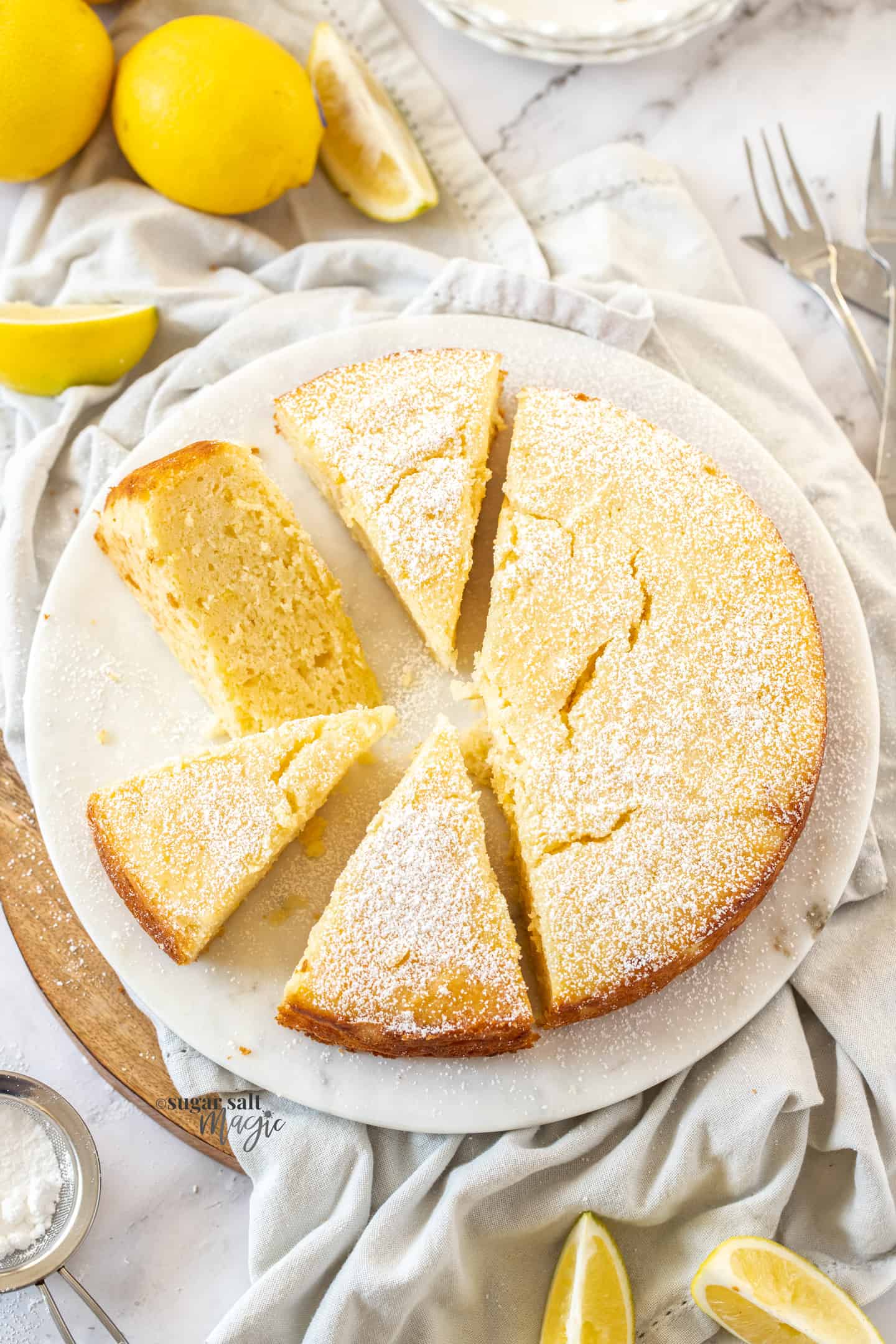Top down view of a whole lemon ricotta cake cut into slices.