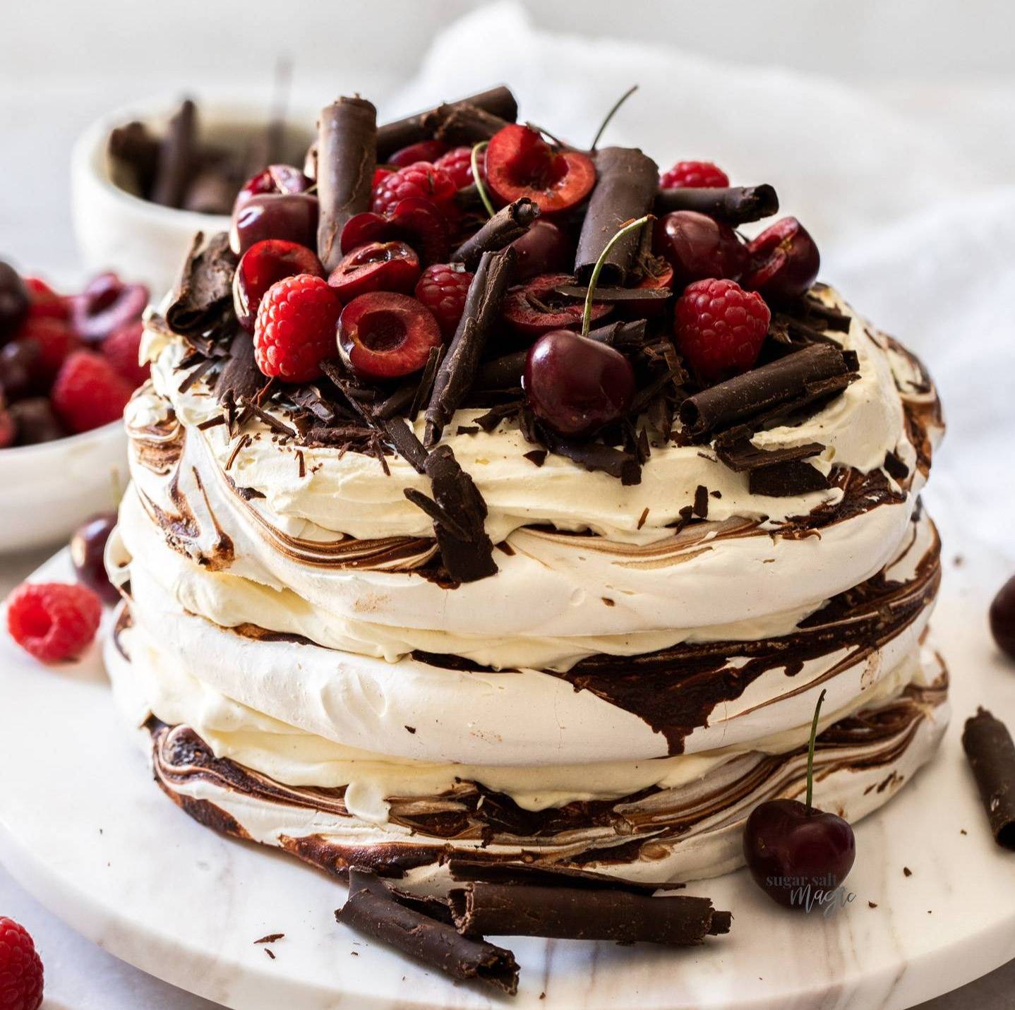 A triple layer chocolate meringue cake on a marble platter.