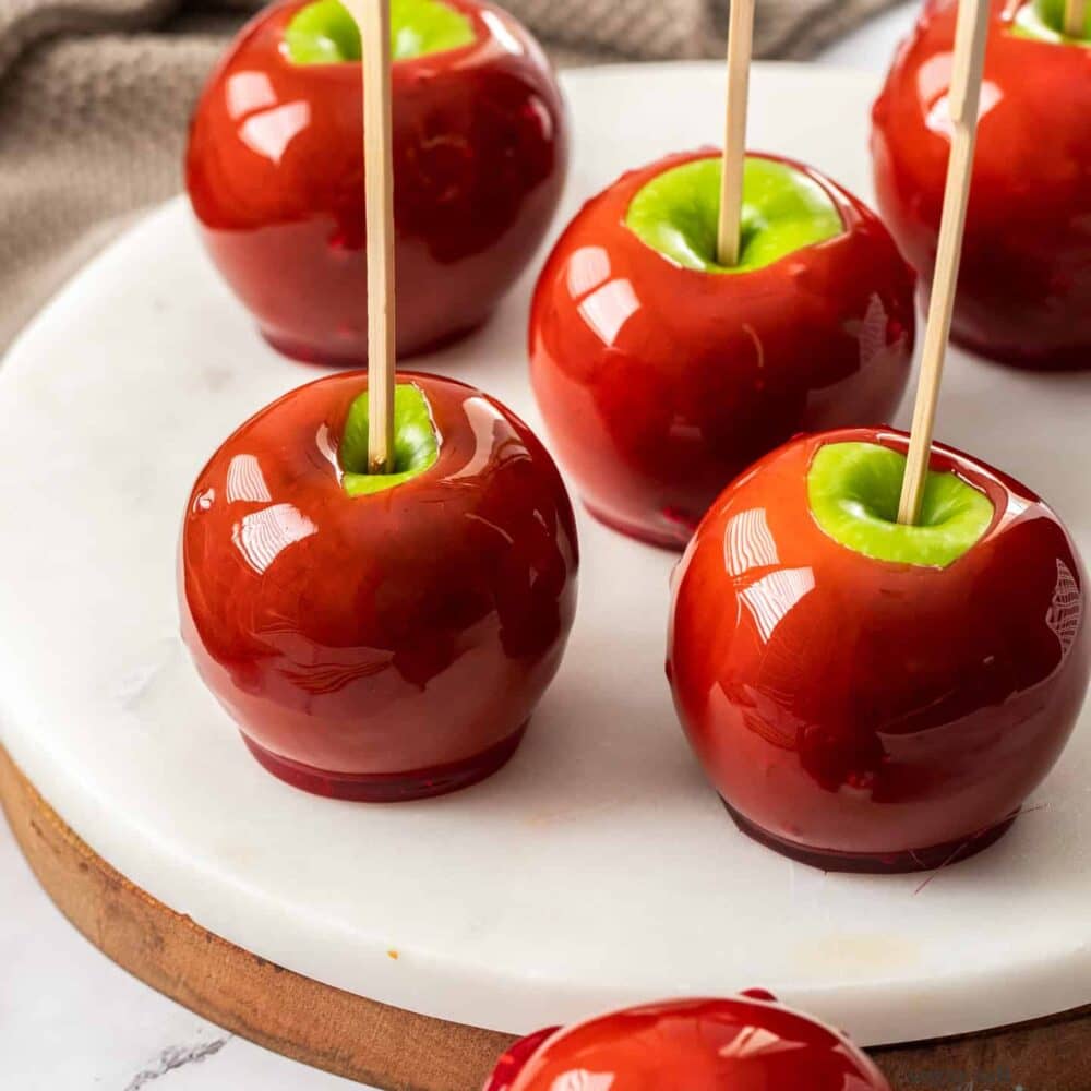 4 apples coated in toffee with sticks poking out.