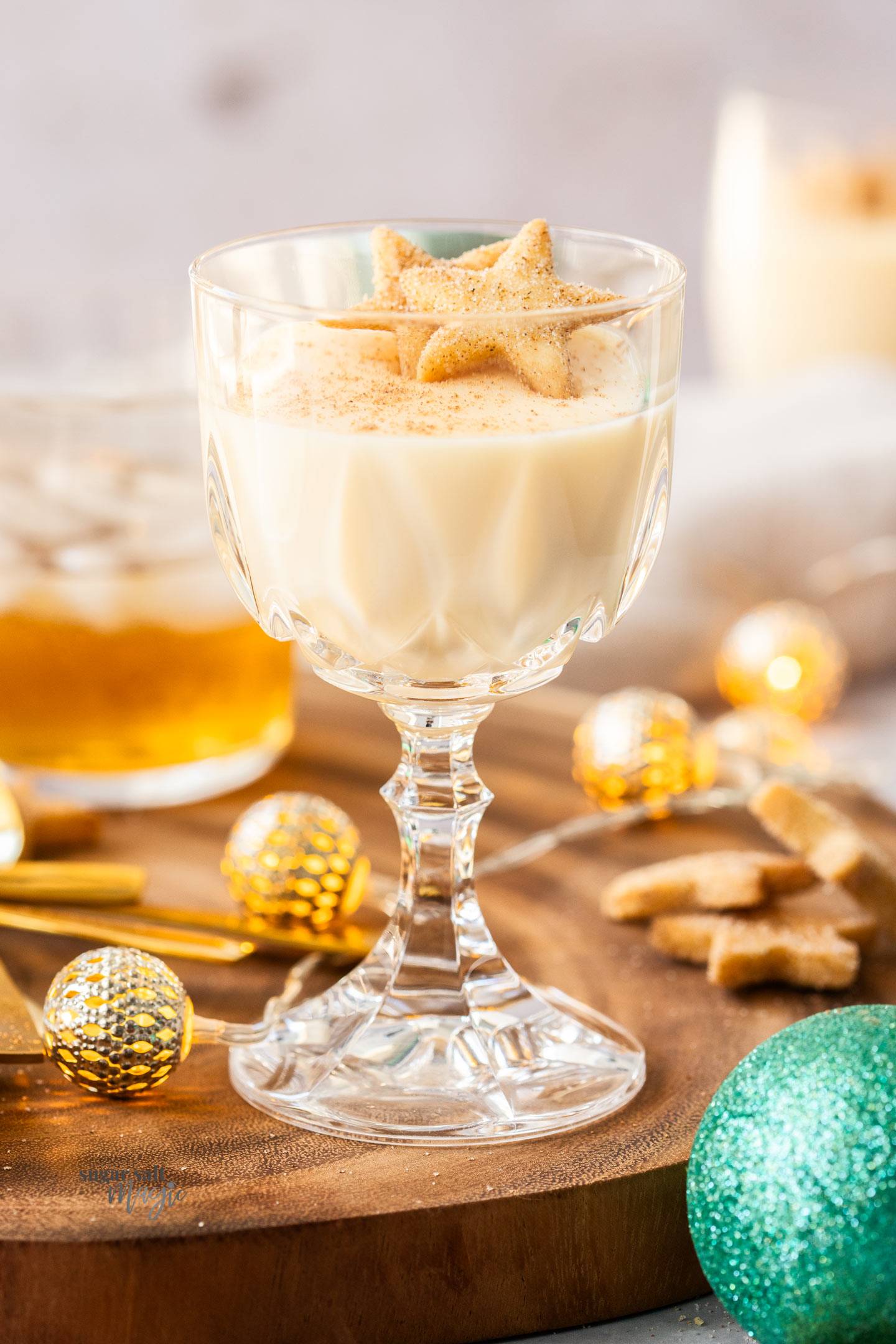 A crystal wine glass filled with eggnog panna cotta and topped with shortbread cookies.