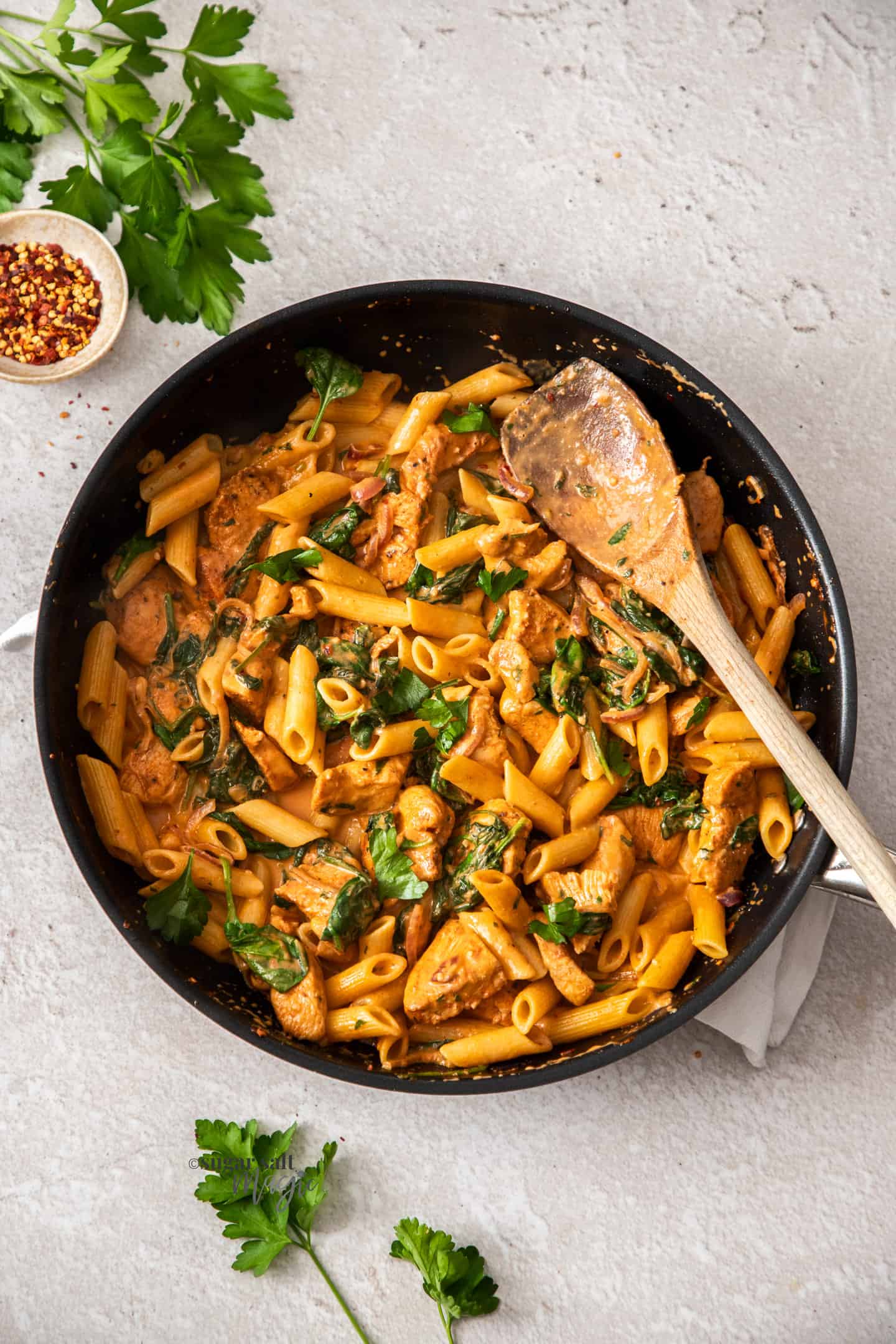 Top down view of creamy chicken and penne pasta in a skillet.