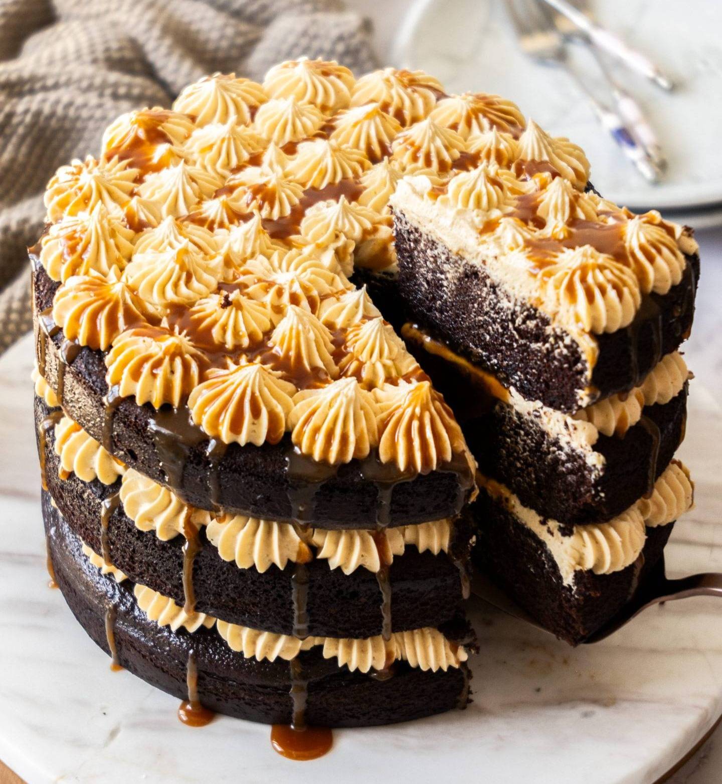 A 3 layered chocolate cake with buttercream and caramel drizzling down.