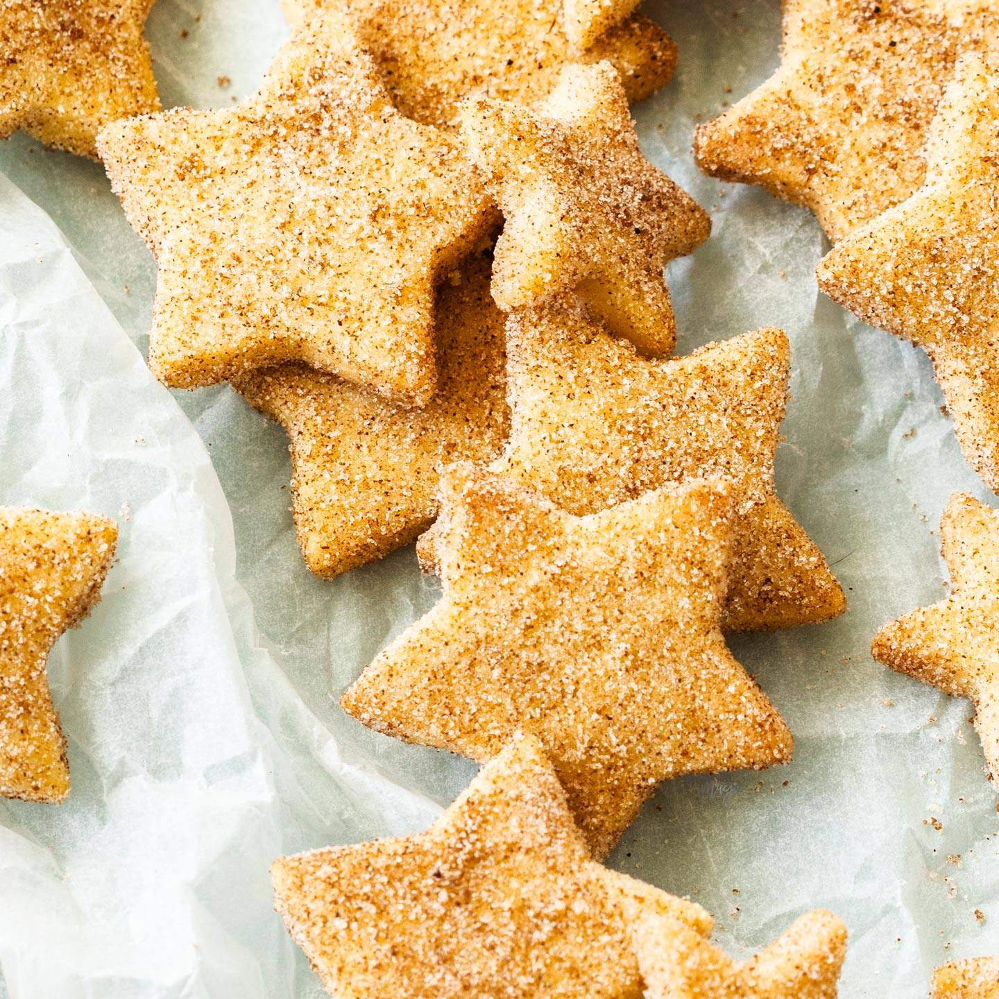 Top down view of shortbread stars on a crumpled sheet of baking paper.