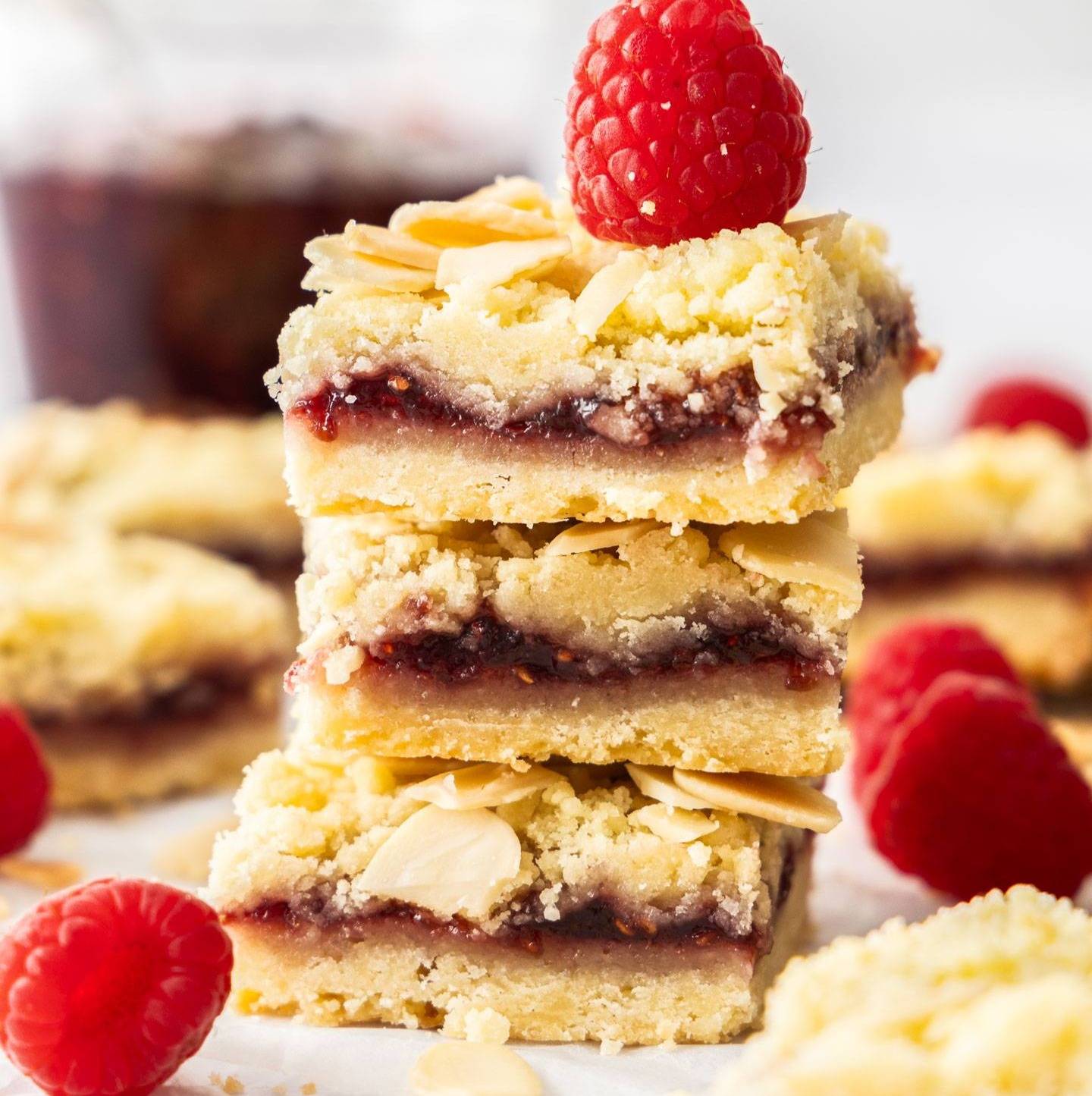 A stack of 3 raspberry shortbread bars topped with a fresh raspberry.