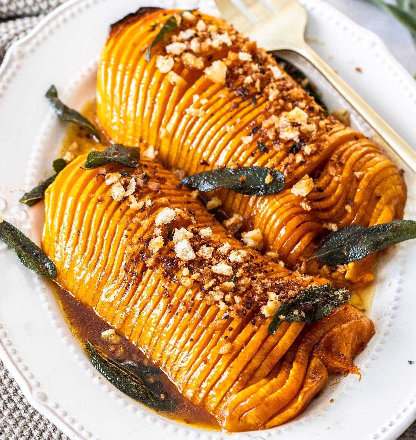 Two halves of butternut squash, hasselback style on a platter.