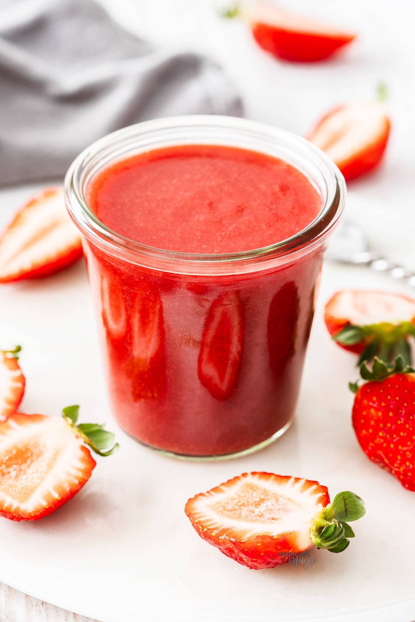 A glass jar filled with strawberry sauce.