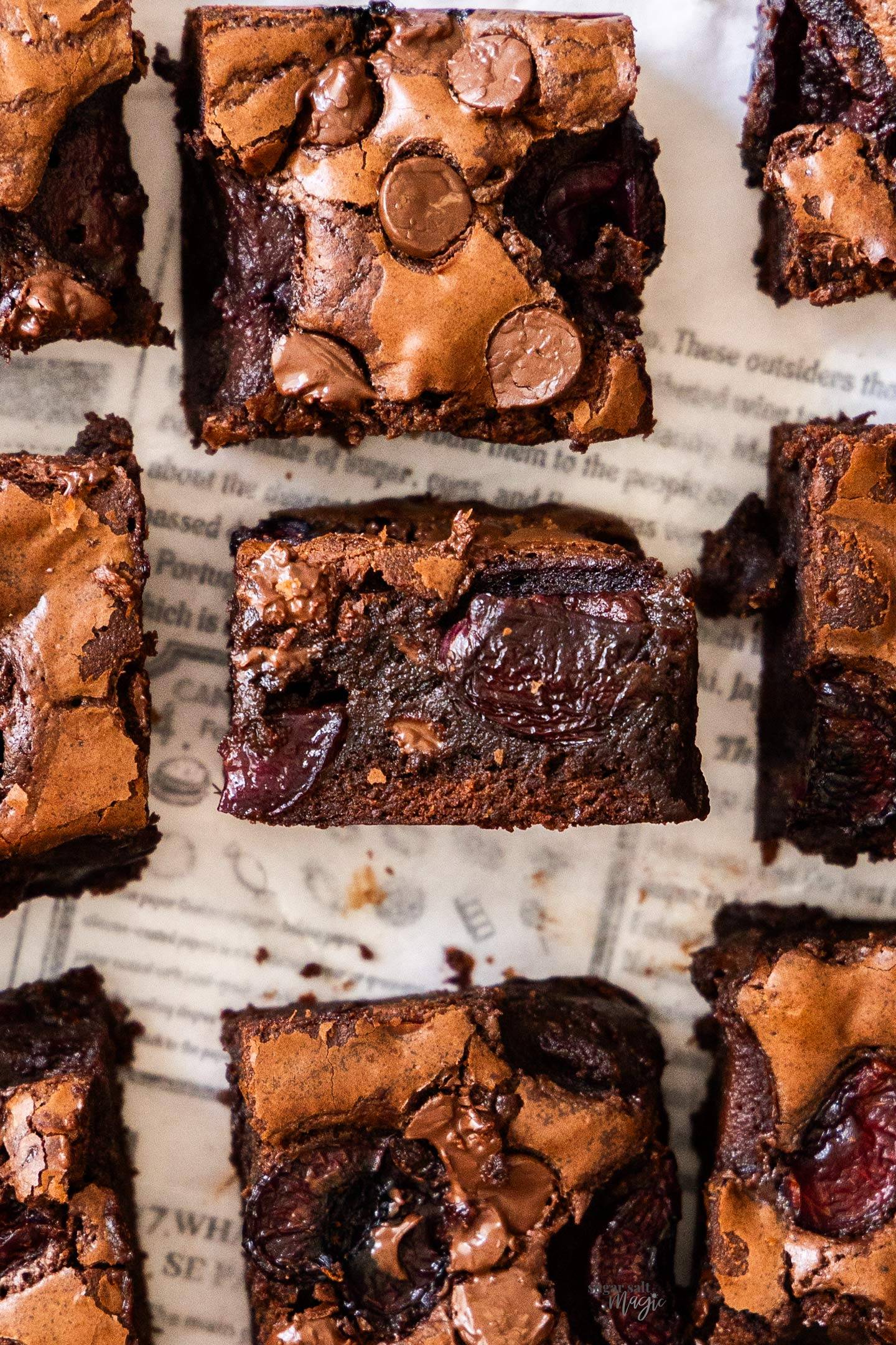 Top down view of brownie squares topped with chocolate chips and cherries.