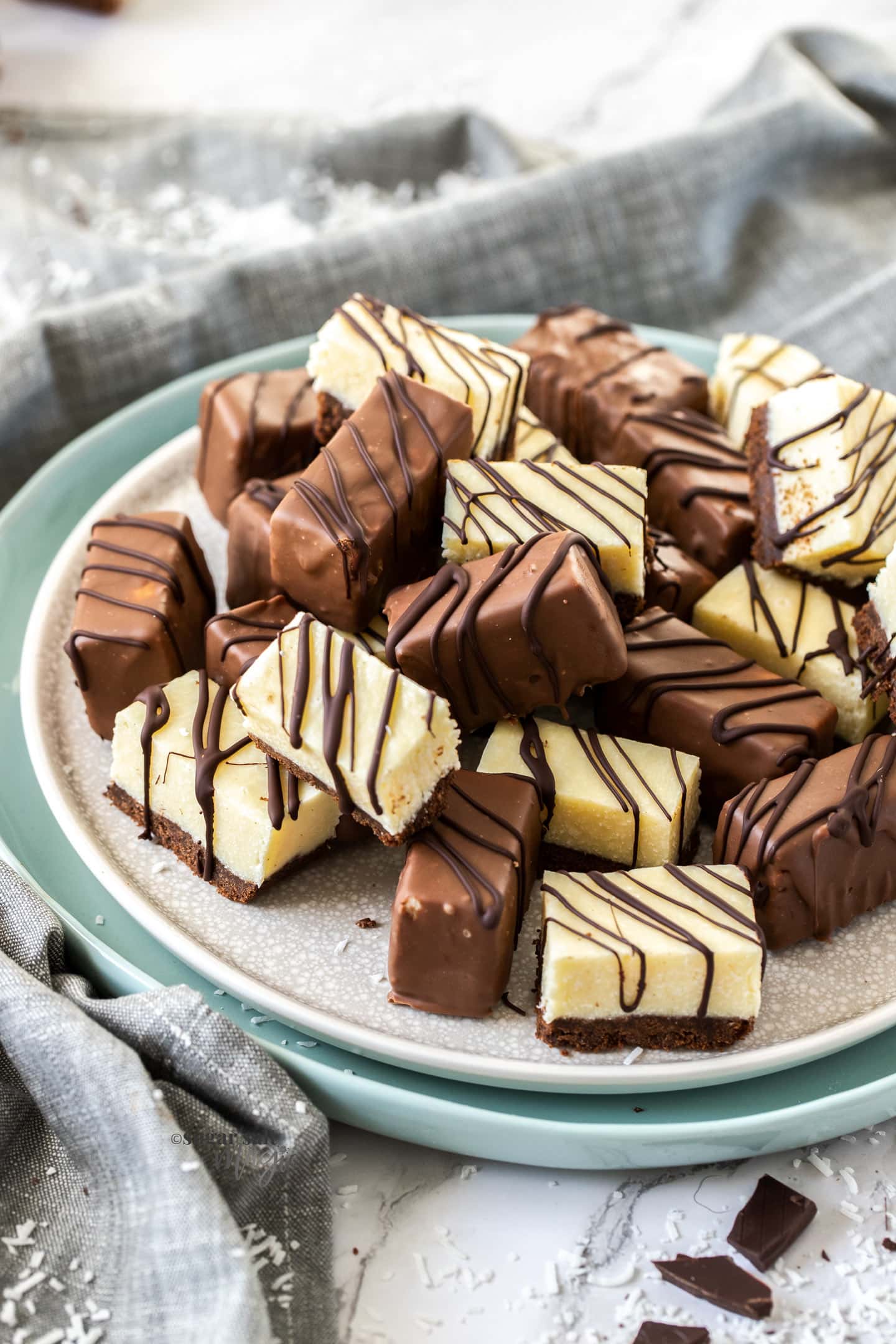 A plate topped with a pile of chocolate coated coconut fudge pieces.