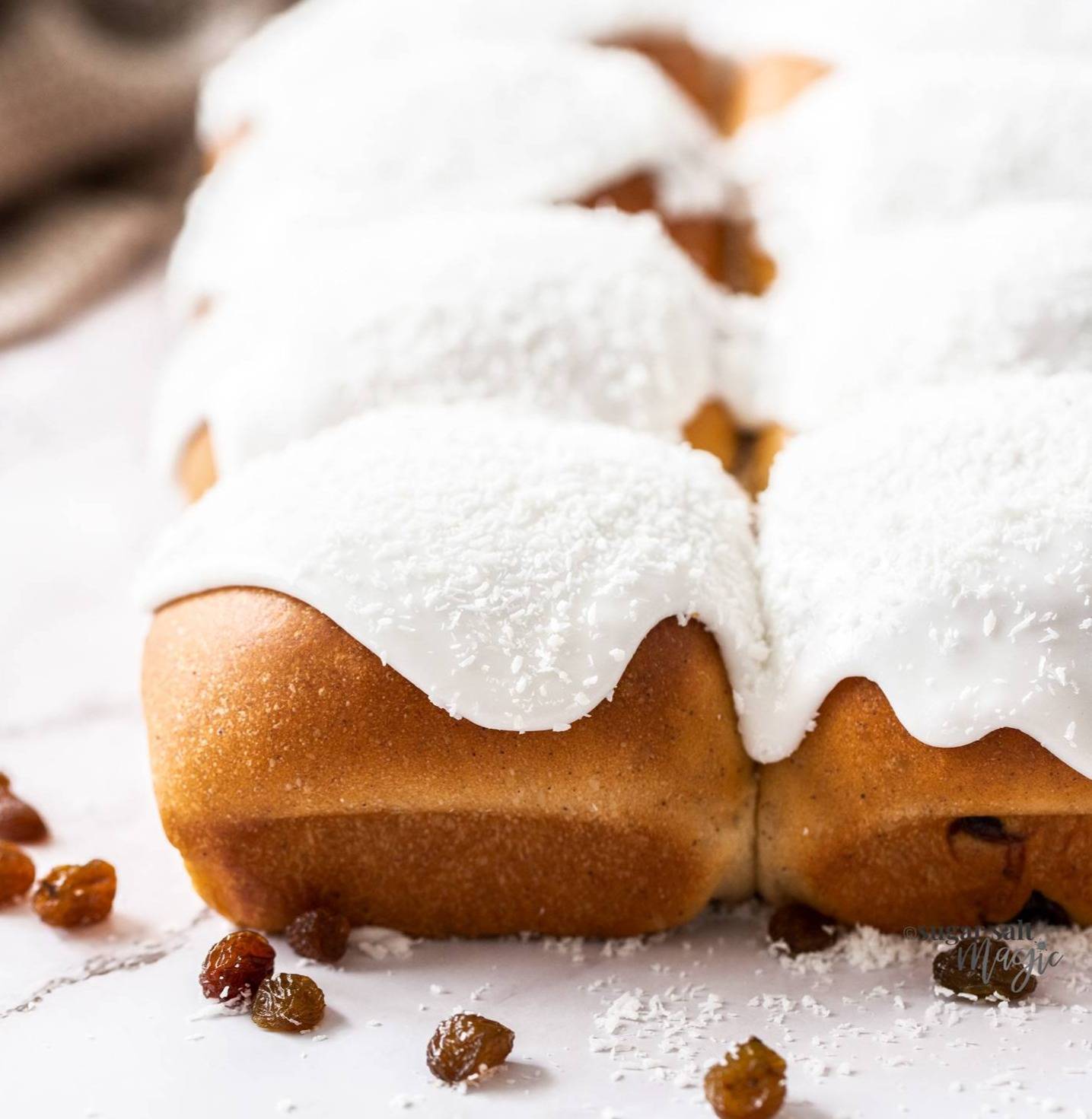 Closeup of a batch of iced buns with white icing.