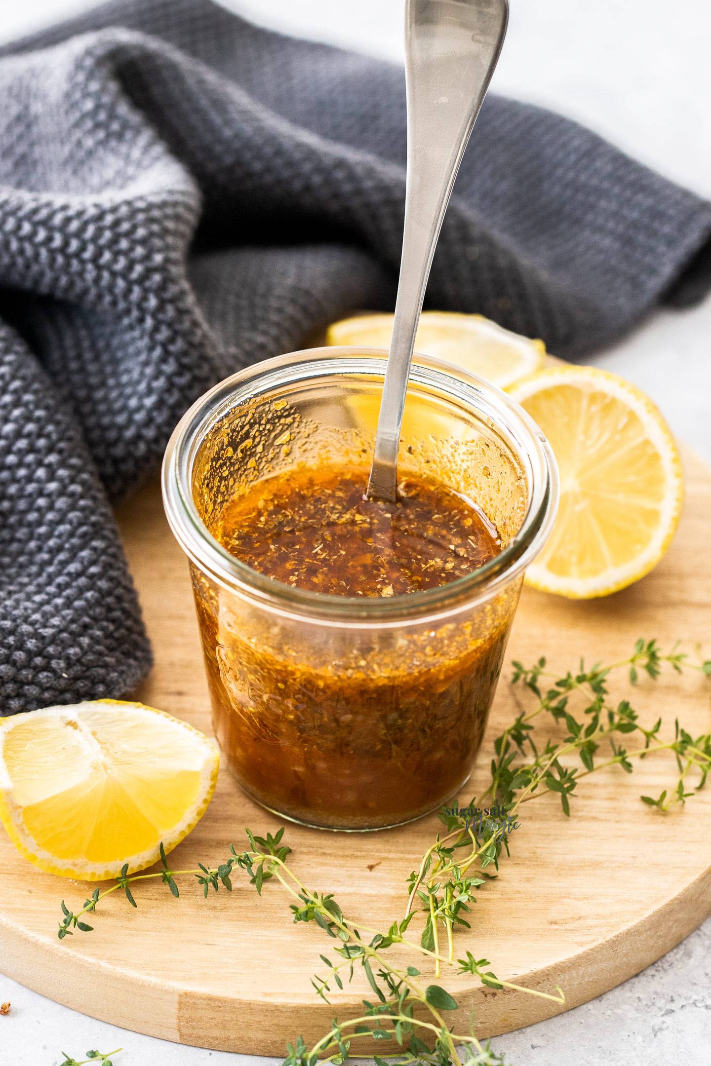 A small glass jar filled with a herby marinade.