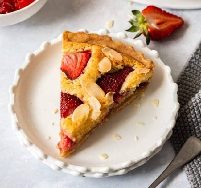 A slice of strawberry frangipane tart on a dessert plate.