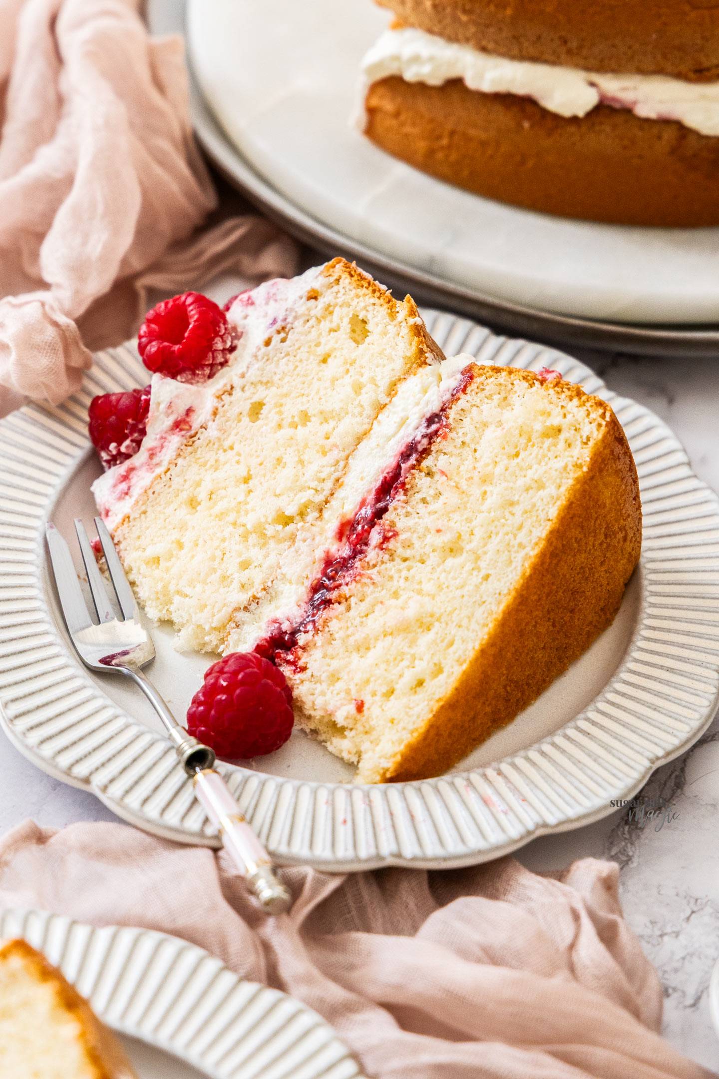A slice of raspberry sponge cake on a dessert plate.