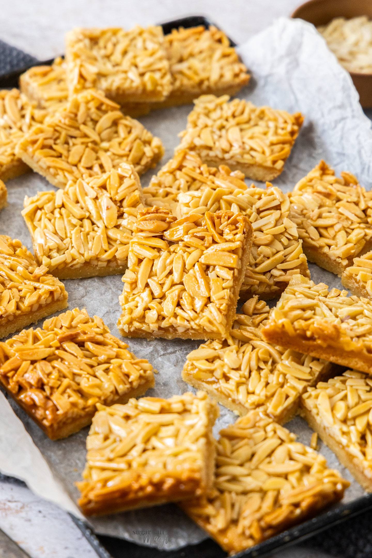 A batch of honey almond slice on a dark tray.