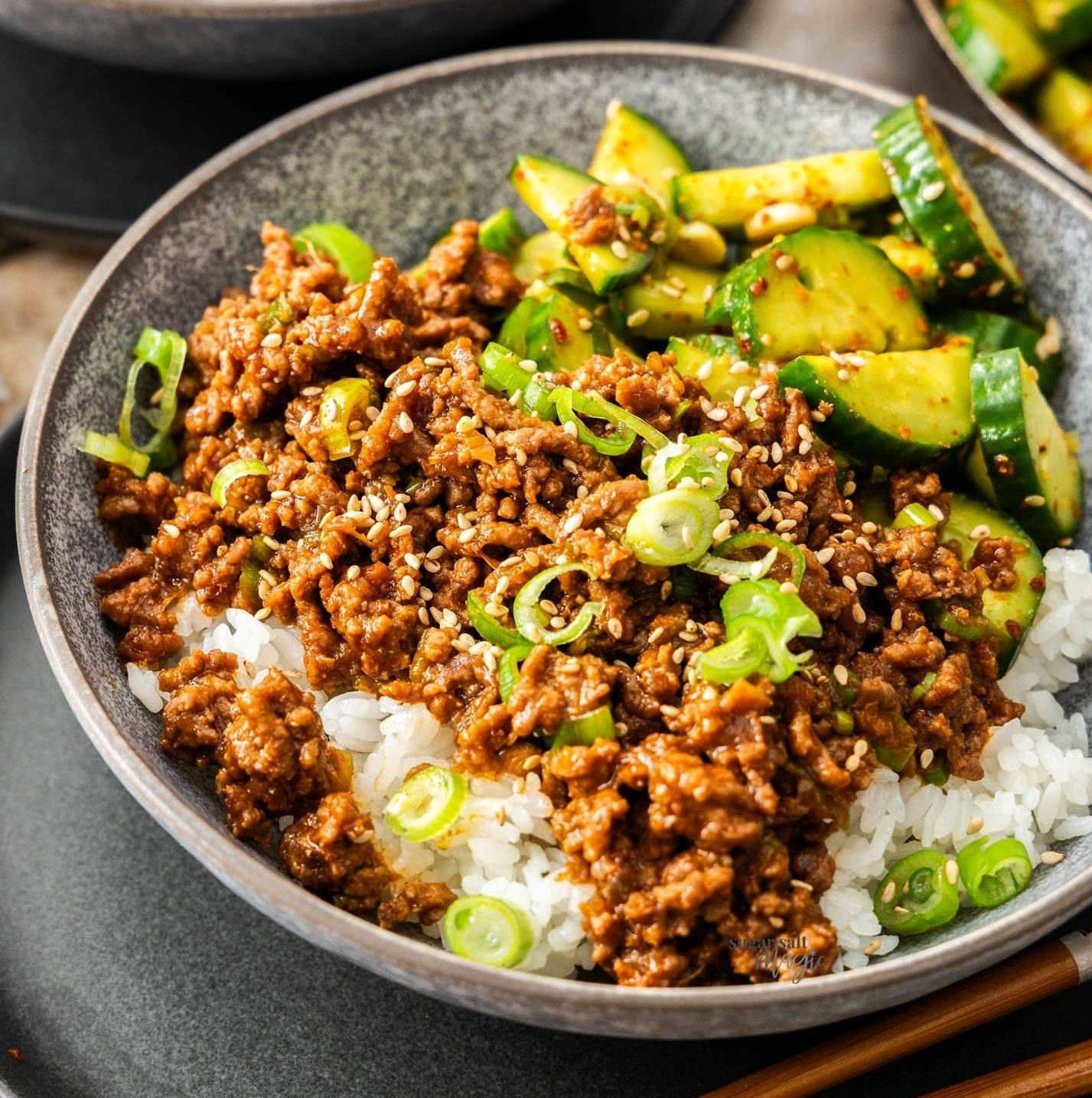 A bowl filled with rice and topped with loads of beef mince and cucumbers.