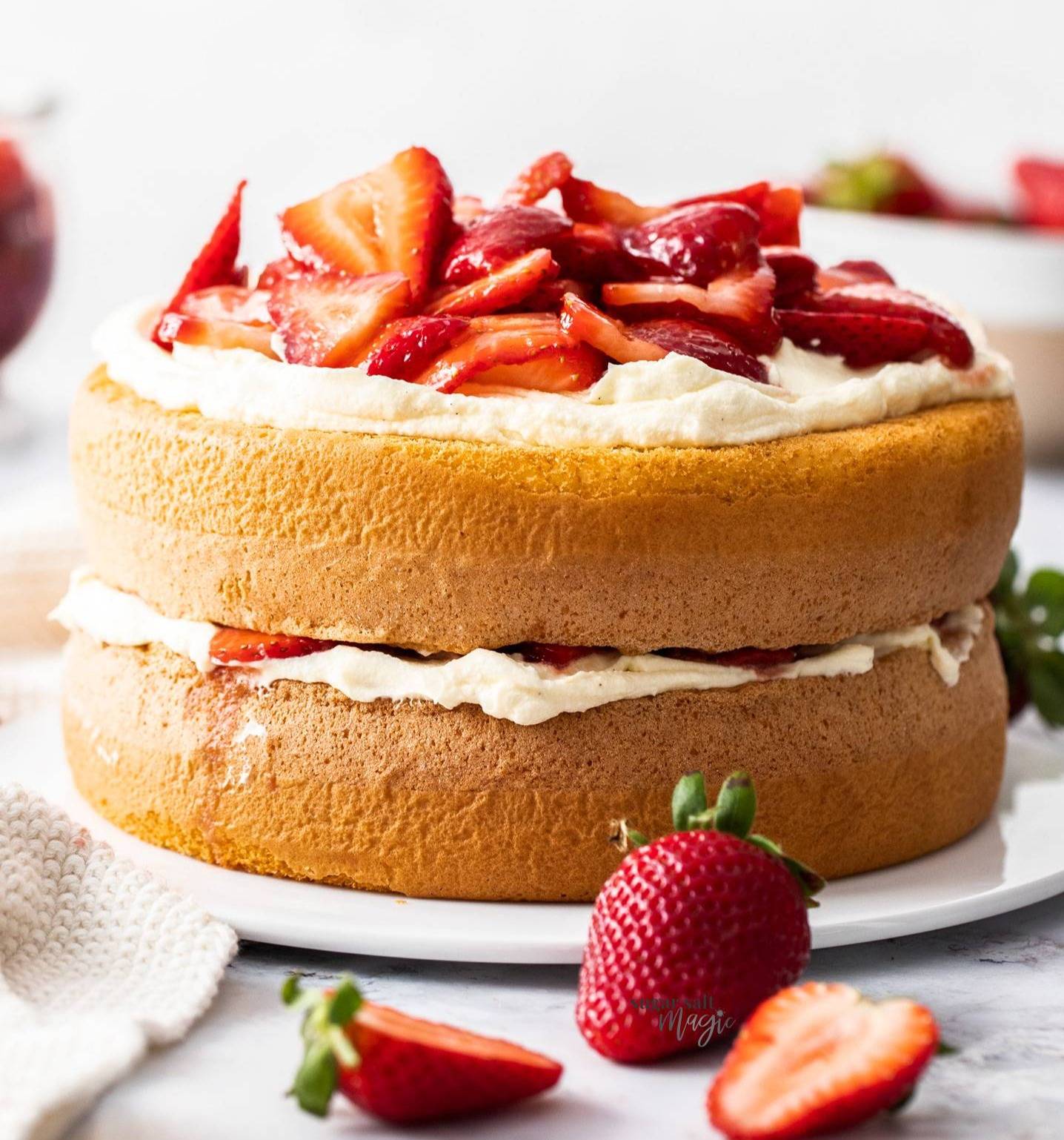 A double layer sponge cake topped with cream and strawberries.