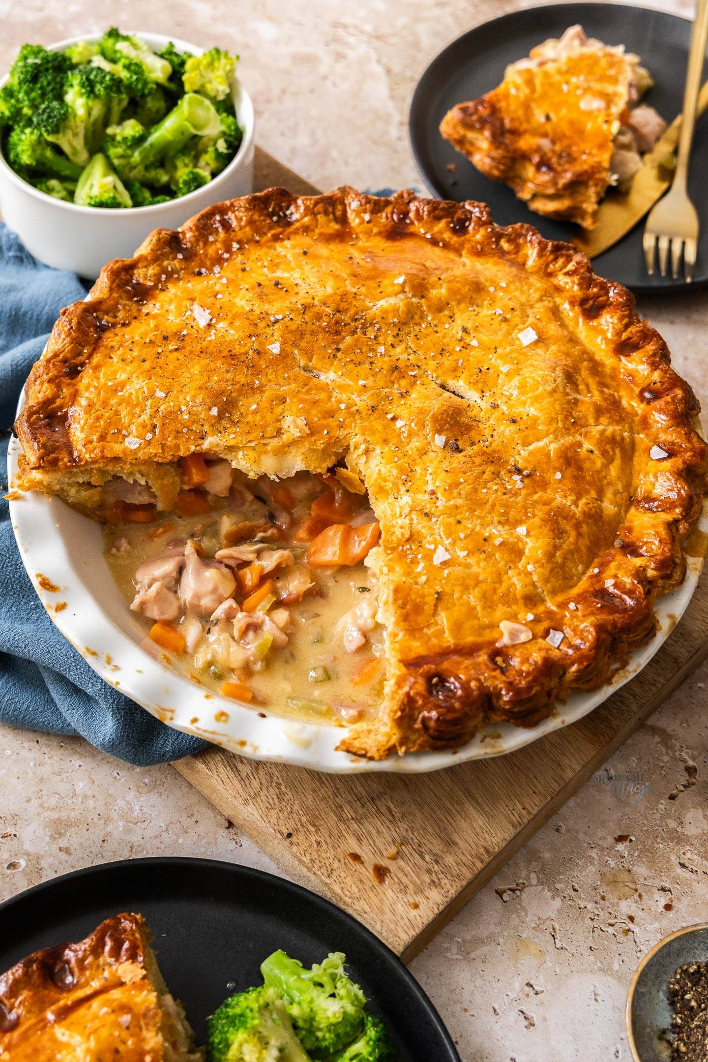 A whole chicken pie with a wedge cut out to show the filling inside.