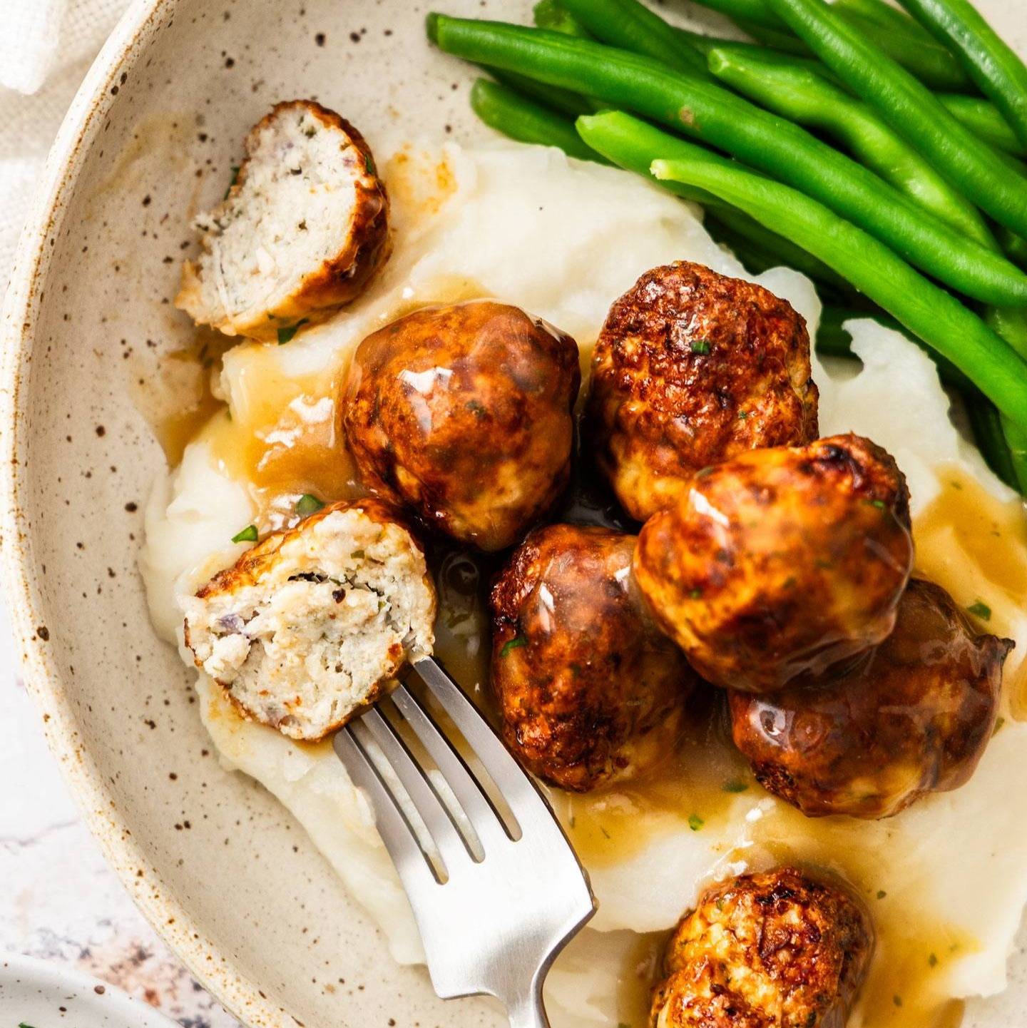 Meatballs with gravy on top of mashed potato.