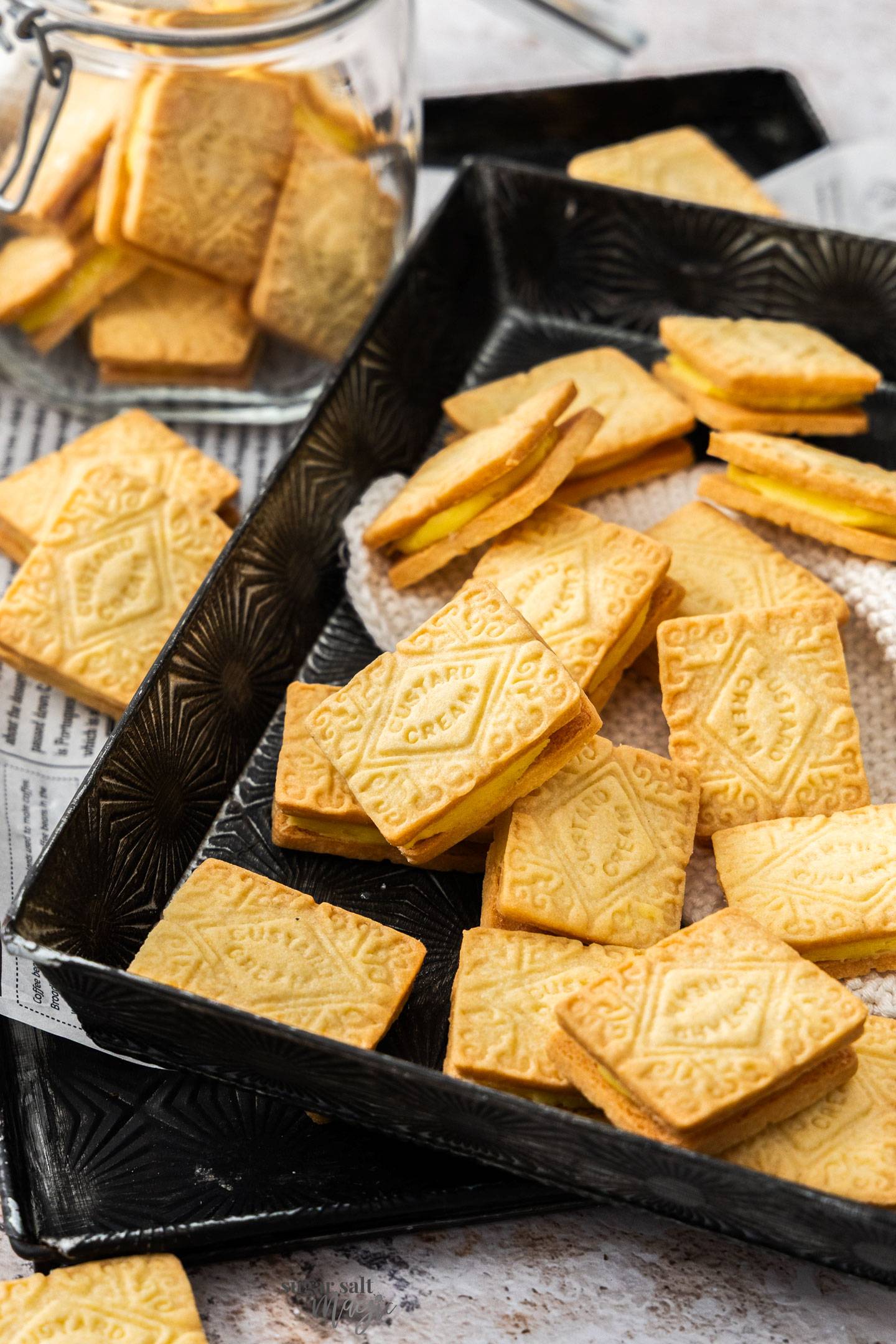 A batch of custard creams on a metal tray.