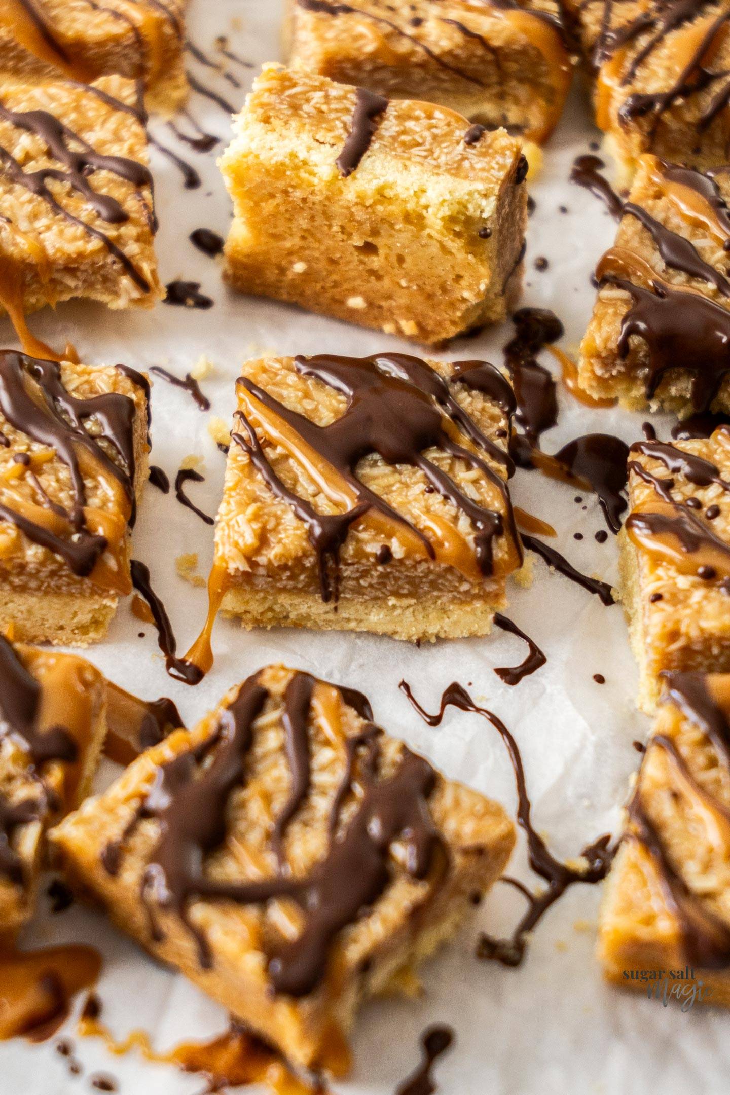 A batch of chewy caramel coconut bars topped with a drizzle of chocolate.