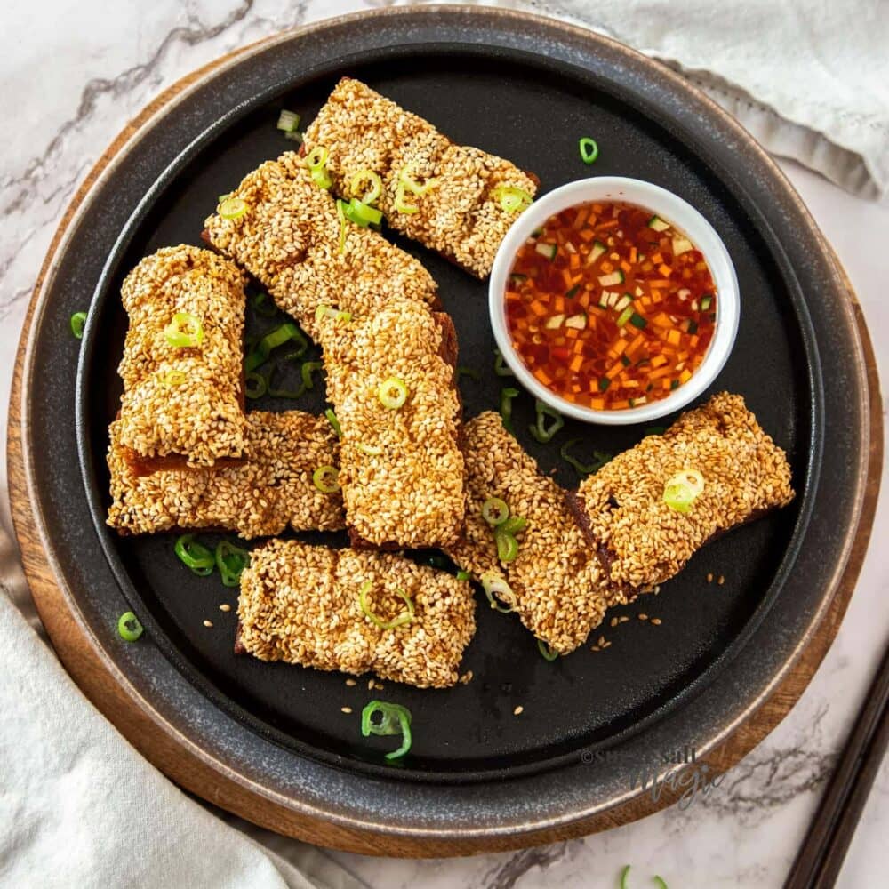 Top down view of a batch of sesame prawn toasts on a plate.