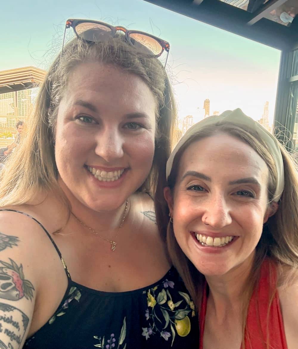 Hayley and Chelsea, two white women with blonde hair wearing dresses, at an outdoor concert on a rooftop in Chicago
