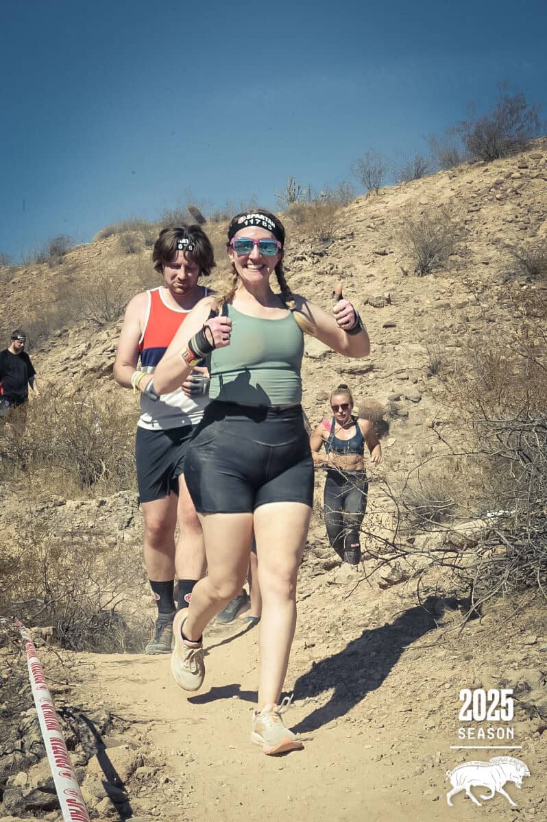 Hayley running through the Arizona landscape giving 2 thumbs up with her brother trailing behind her