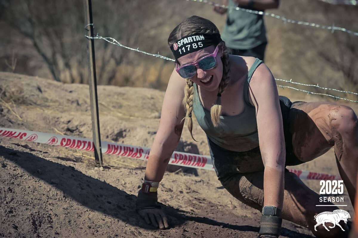 Hayley climbing through mud under barbed wire during the Sparan 5K
