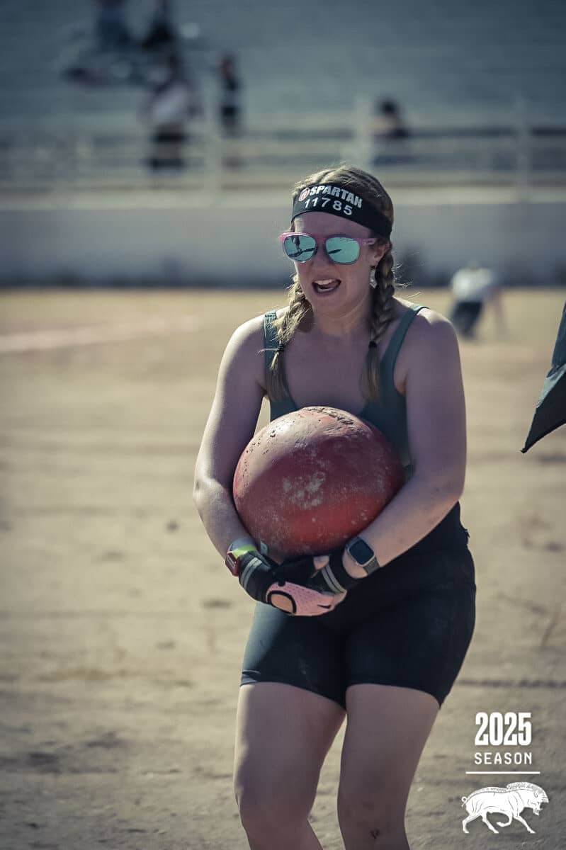 hayley carrying a 75lb boulder in the Atlas Carry during the Spartan Race