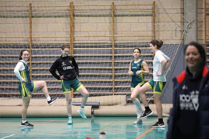 Athletes in uniform practicing drills indoors.