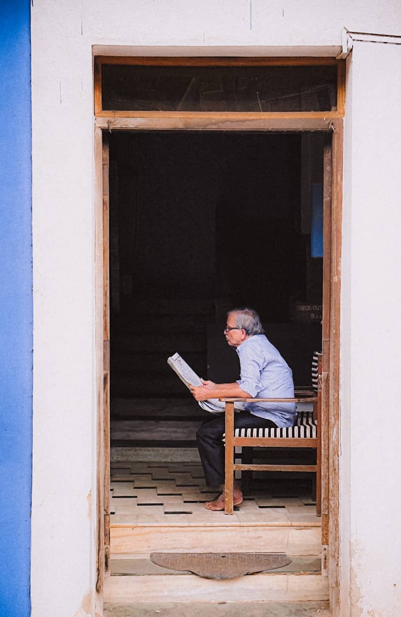 Elderly man reading newspaper in doorway