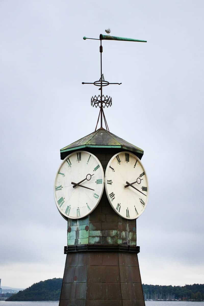 A clock tower with two faces and a weather vane