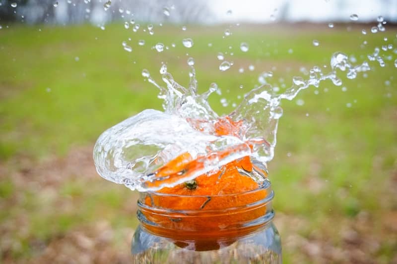 Water splashing onto carrots in a jar outdoors