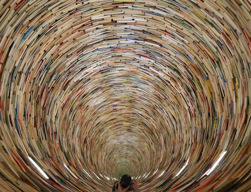 Endless tunnel made of stacked books leading to a person