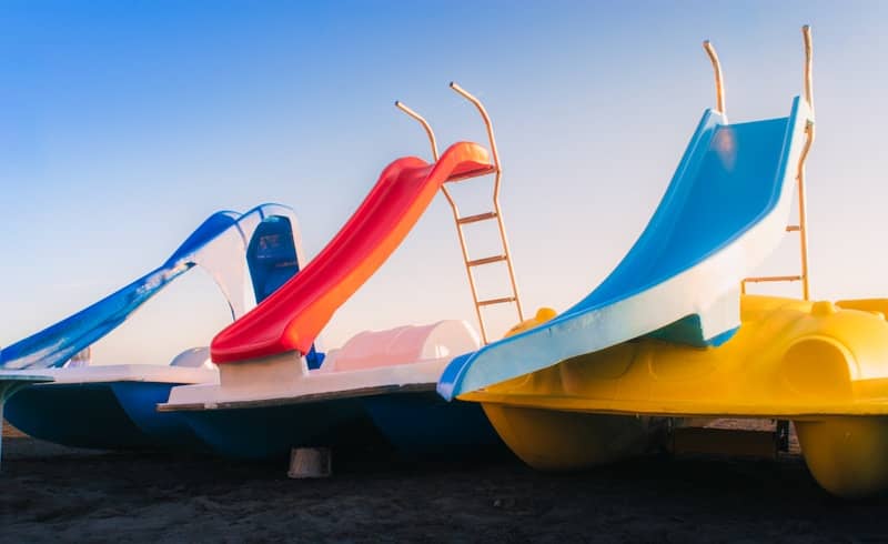 Three colorful pedal boats with slides under a clear sky.