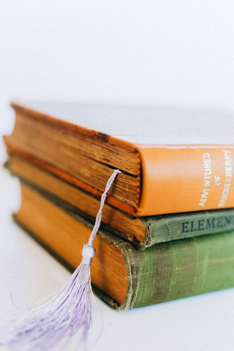 A stack of two vintage books with a light purple tassel bookmark