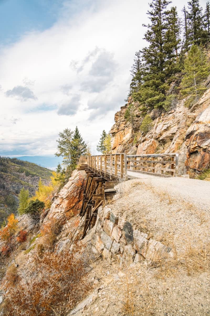 Wooden trestle bridge and dirt path on a rocky mountainside.