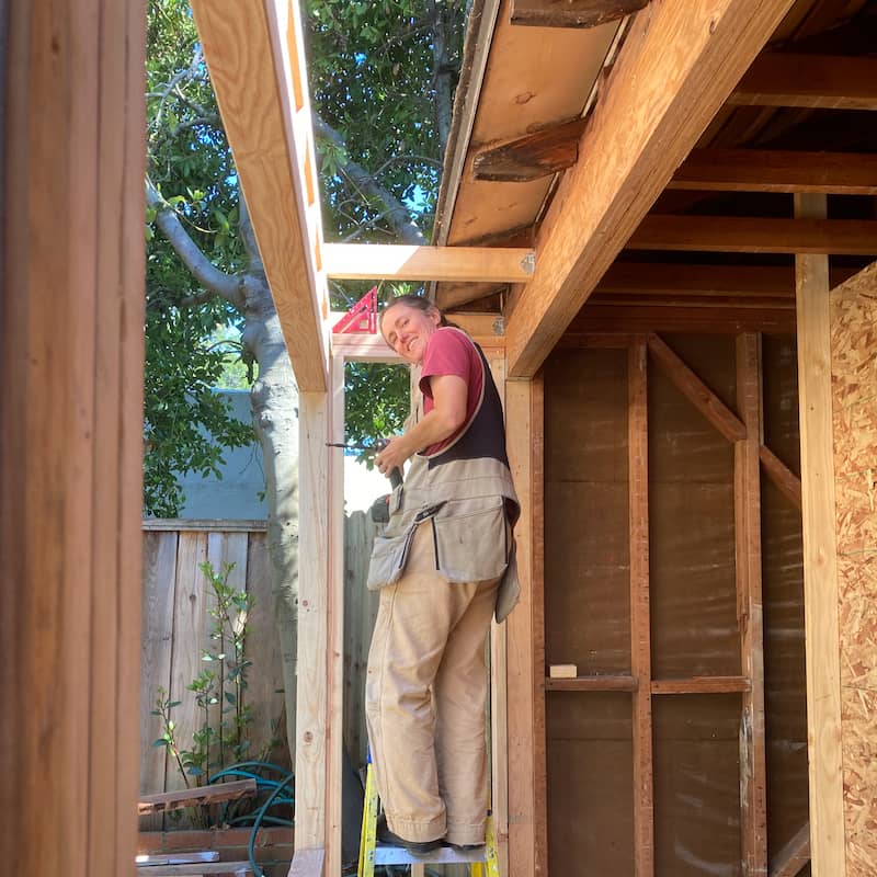 Me standing on a ladder working on open framing during house construction